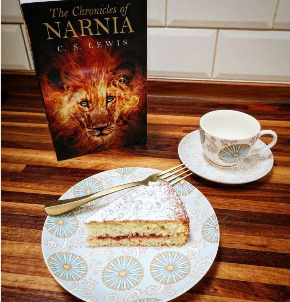 The Lion The Witch and The Wardrobe novel posed next to cake