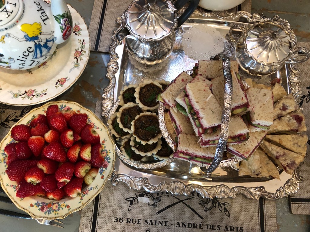 An overhead view, showing the Alice in Wonderland teapot, strawberries, the tea set, the mushroom tarts, sandwiches, and scones.